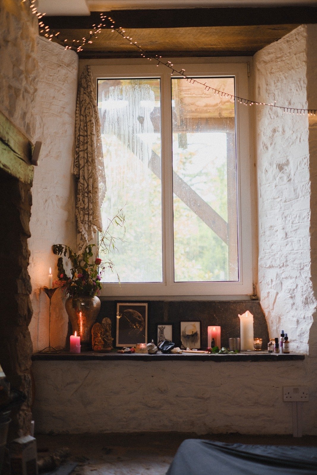 A window altar with candles, flowers, and sacred objects