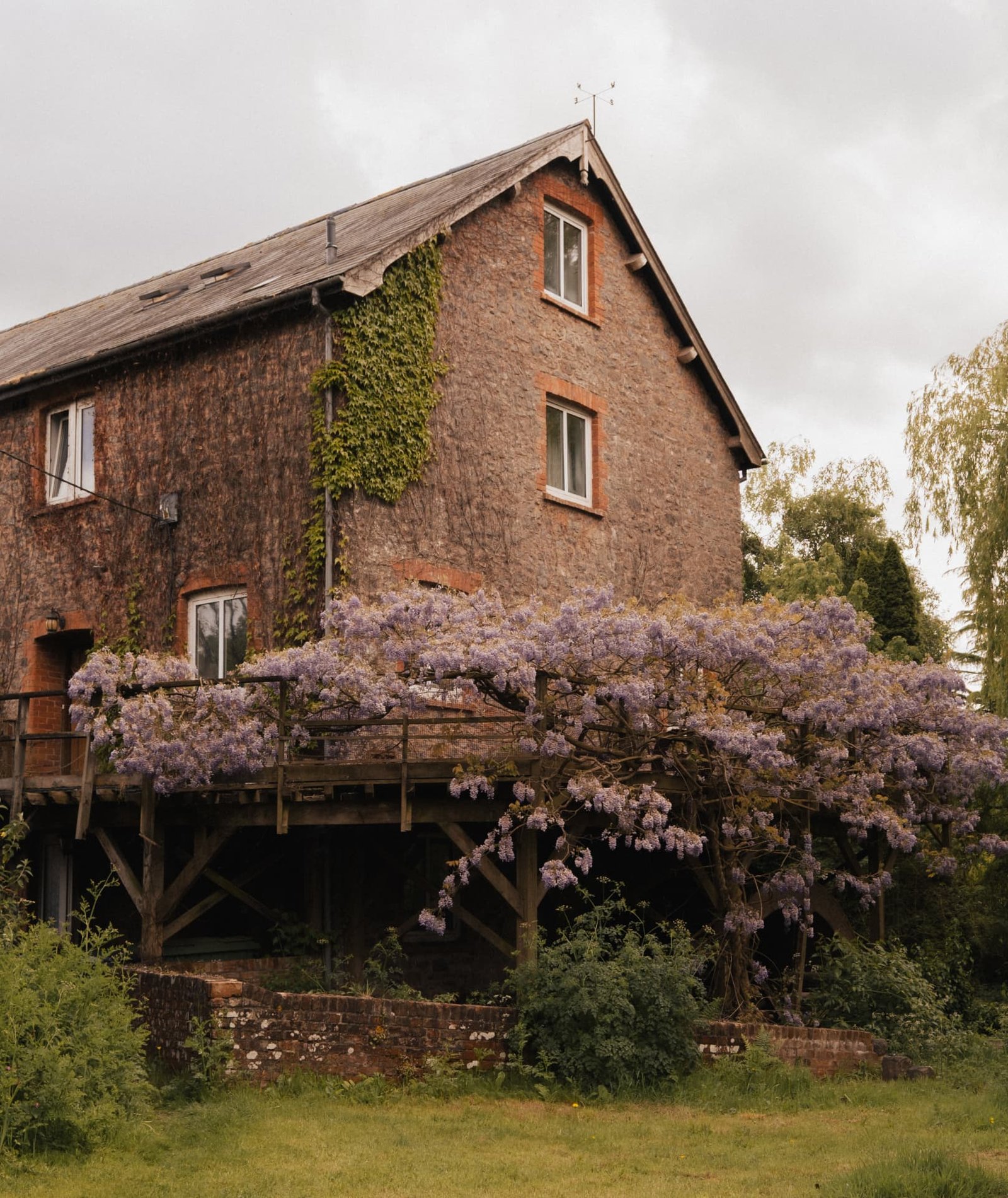 The stone retreat barn draped in flowering wisteria