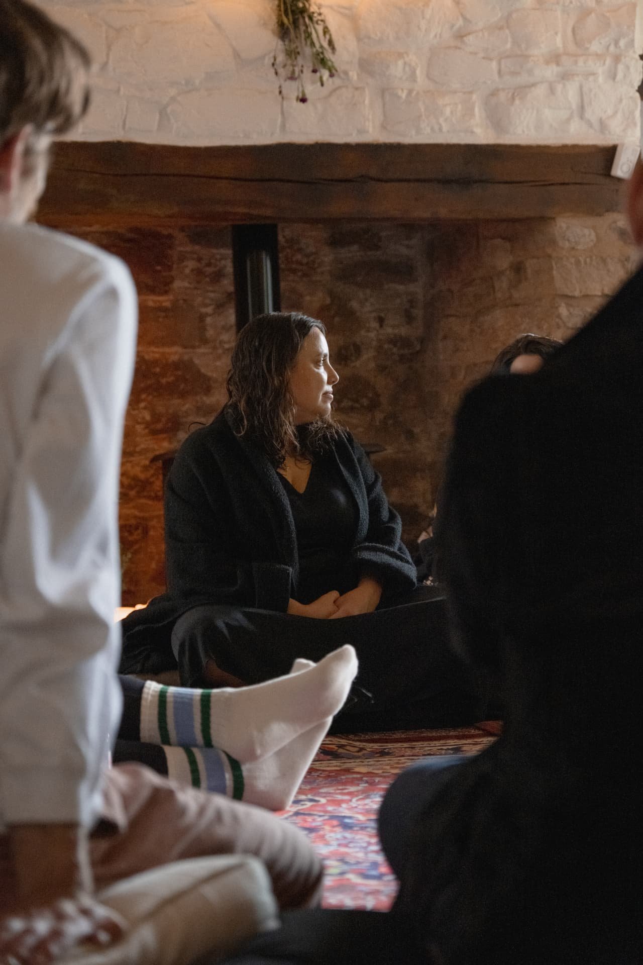 A participant seated in quiet reflection by the fire
